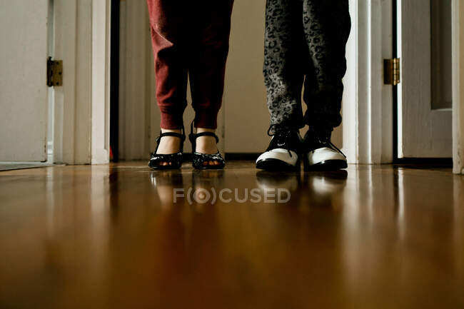 Two young children wearing heels and shoes standing in a hallway — Stock Photo