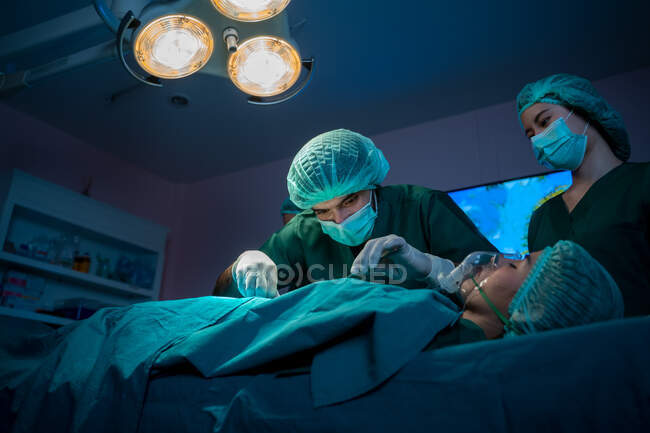 Cirujano médico de grupo que realiza operaciones quirúrgicas en quirófano moderno, atención médica y concepto médico. - foto de stock