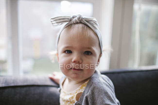 Portrait of cute one year old girl wearing headband inside at home — Stock Photo