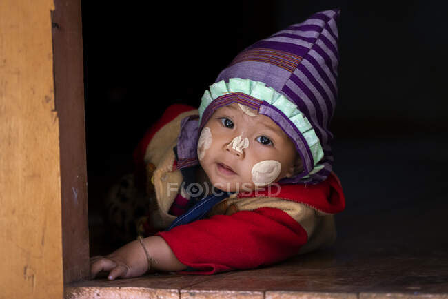 Lindo chico birmano con sombrero arrastrándose en el suelo, Loikaw, Myanmar - foto de stock