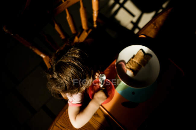 Вид зверху на молоду дівчину, що їсть її сніданок за кухонним столом — стокове фото