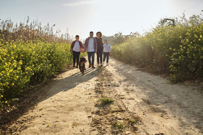 Счастливая семья, гуляющая в сельской местности со своим питомцем — стоковое фото