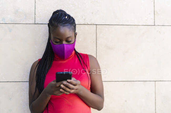 Mujer con trenzas africanas enviando un mensaje desde su teléfono inteligente - foto de stock