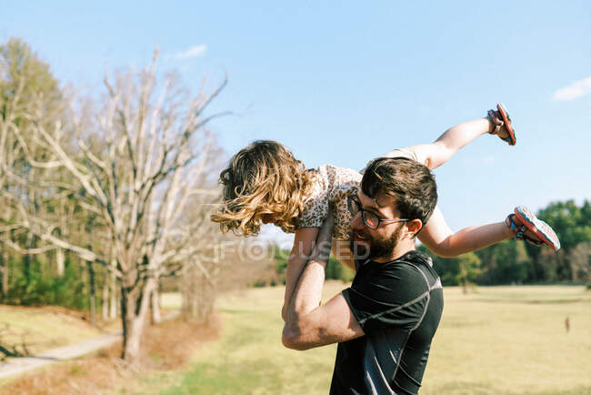 Father carrying his little toddler daughter on his shoulders — Stock Photo