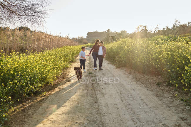 Mother walks along a country trail while talking with her children — Stock Photo