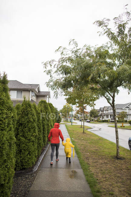 Vista posteriore della madre che cammina con il bambino sul marciapiede. — Foto stock