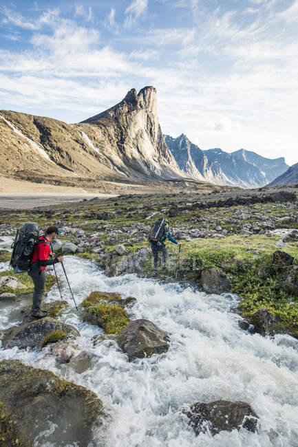 Dos mochileros que caminan por el valle montañoso, la isla de Baffin - foto de stock