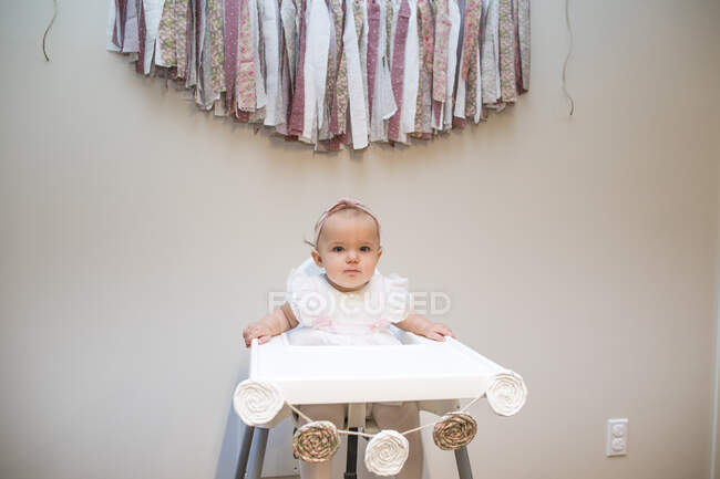 First birthday, baby girl sitting under birthday banner — Stock Photo