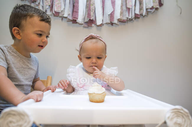 Brother helps his one year old sister on her first birthday — Stock Photo