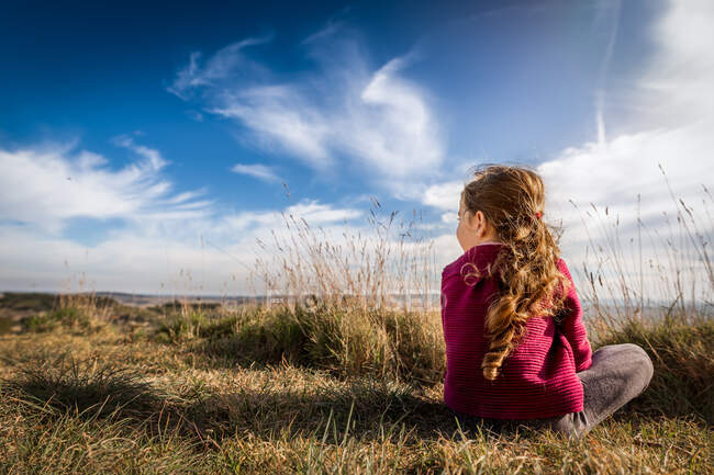 Дівчинка сидить на сонці, а влітку повертається до фотоапарата на півдні Франції. — стокове фото