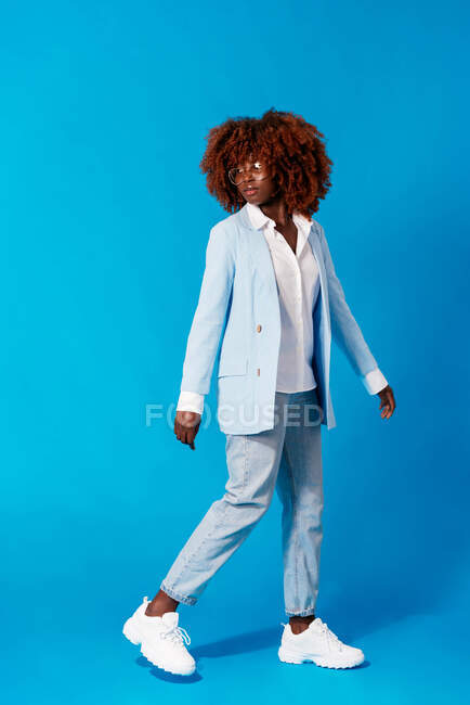 Retrato de mujer africana de moda de pie sobre fondo azul - foto de stock