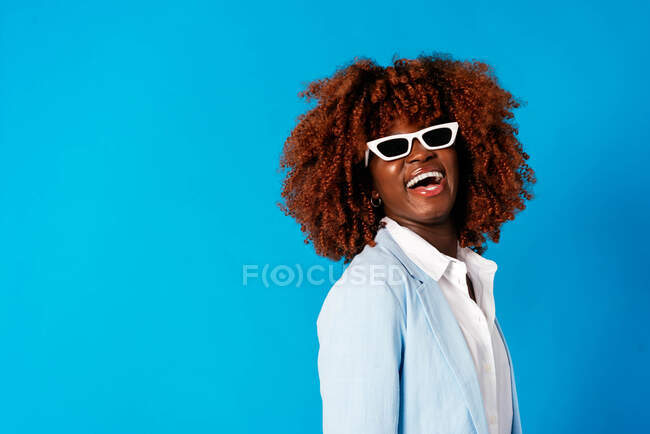 Trendy young female model wearing blue blazer against blue background — Stock Photo