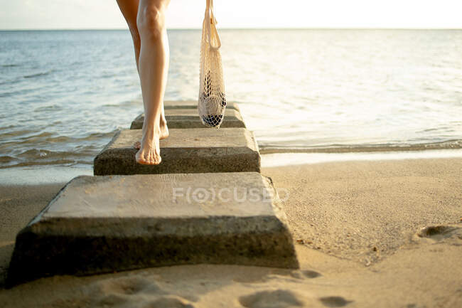 Pernas de mulher com saco na praia — Fotografia de Stock
