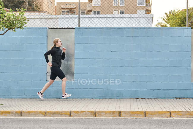 Young woman in sportswear running through the city — Stock Photo