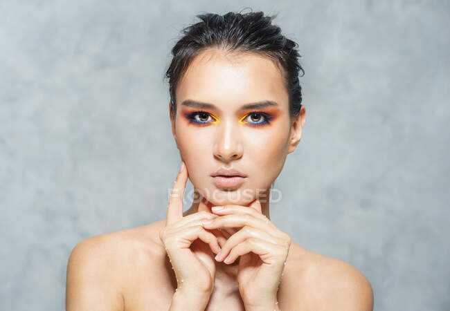 Retrato de belleza para chica bronceada con maquillaje y cabello húmedo en gris - foto de stock