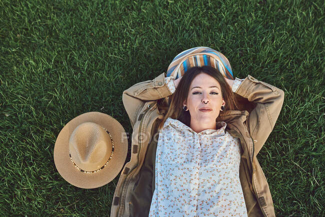 Frau liegt auf einer Wiese. Sie ruht sich glücklich aus. — Stockfoto