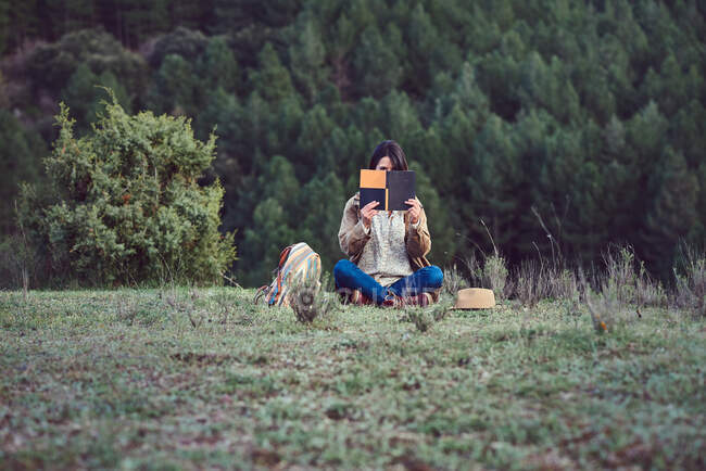 Frau in den Bergen liest auf einer Wiese ein Buch. — Stockfoto