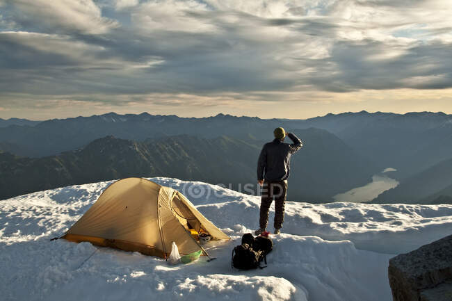 Hiker stands next to tent on mountain summit, Whistler, B.C. Canada. — Stock Photo