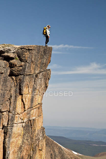 Active and fit female backpacker standing on the edge of a cliff — Stock Photo