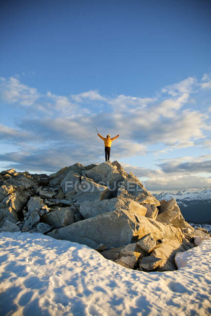 El montañista levanta los brazos después de una subida exitosa a la cima de la montaña. - foto de stock