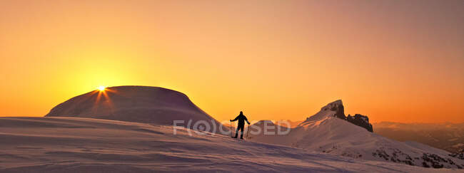 Vista panorâmica do explorador no cume de montanha nevado ao pôr do sol. — Fotografia de Stock
