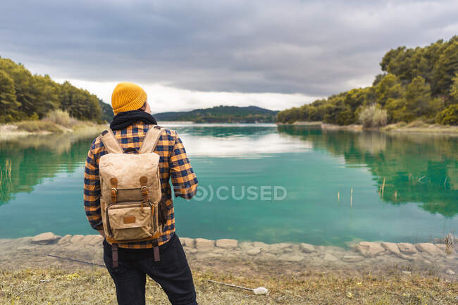 Turista dalla sua schiena guarda bello e calmo lago turchese — Foto stock