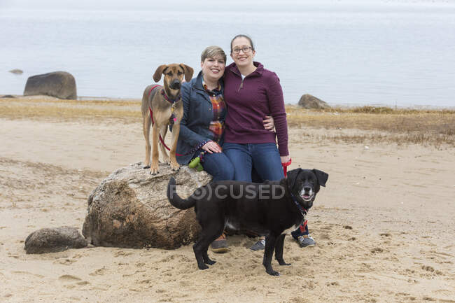 Portrait of same sex female couple with two dogs on Cape Cod beach — Stock Photo