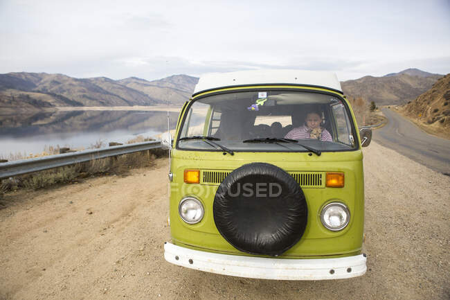 Una mujer y su perro son visibles a través del parabrisas de VW caravana - foto de stock