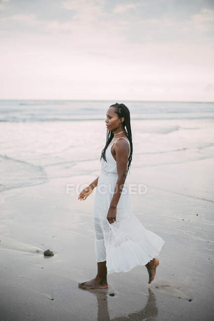 Young beautiful woman in white dress posing on beach — Stock Photo