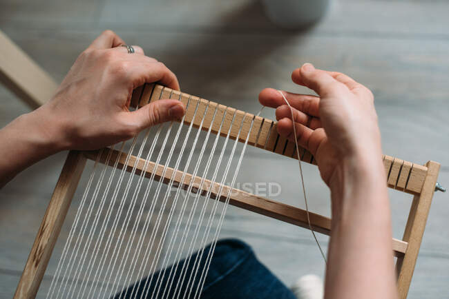 Hands of woman preparing frame for weaving wool rug — Stock Photo