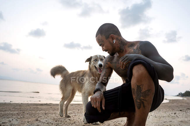 Thai guy on the seashore among the palm trees all in tattoos — Stock Photo