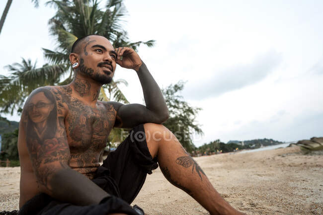 Tailandês na praia entre as palmeiras tudo em tatuagens — Fotografia de Stock