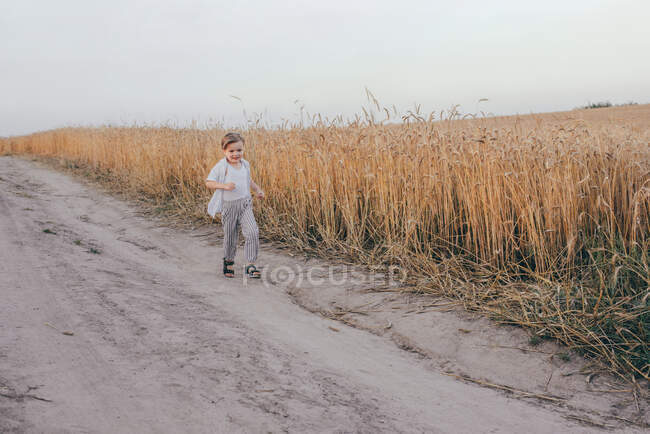 Портрет щасливого п'ятирічного хлопчика, у білій сорочці, що стоїть на полі на зеленій траві. — стокове фото