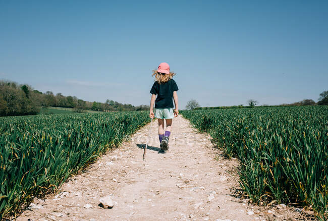 Jeune fille dans un chapeau et un sac à dos marche le long de la route — Photo de stock
