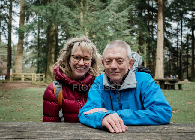 Father and daughter sat on a bench smiling whilst out hiking in the UK — Stock Photo