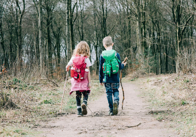 Due bambini che camminano insieme con bastoni e zaini parlando nel Regno Unito — Foto stock