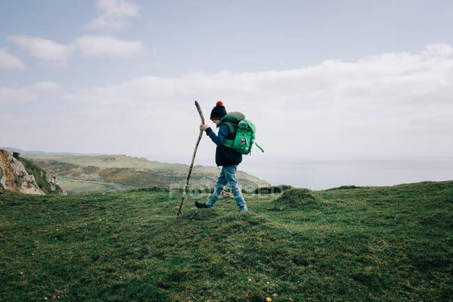 Garçon randonnée le long de la côte jurassique avec un bâton de marche explorer — Photo de stock