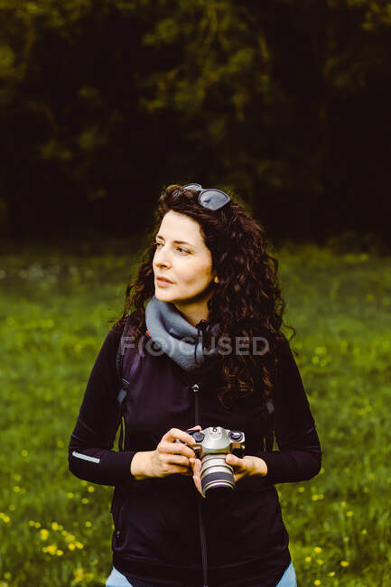 Femme aux cheveux bruns prenant des photos dans la forêt — Photo de stock