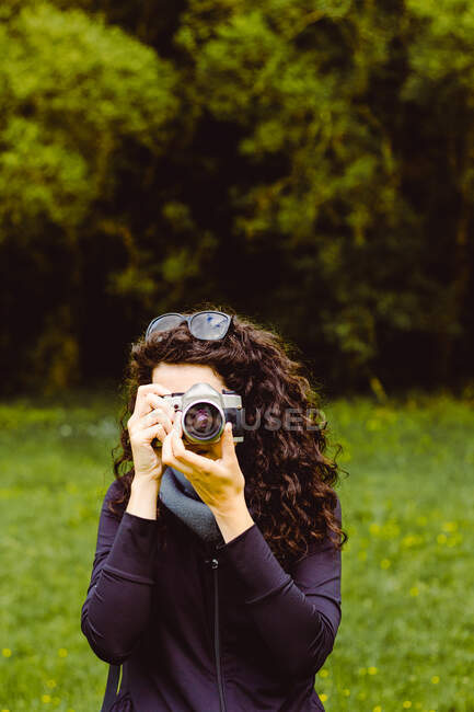 Mujer de cabello oscuro tomando fotos en el bosque - foto de stock