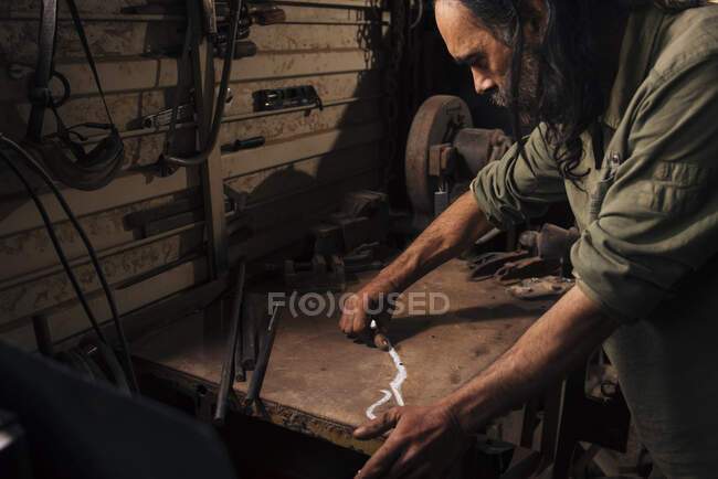 Blacksmith drawing a design for making a pair of scissors. — Stock Photo
