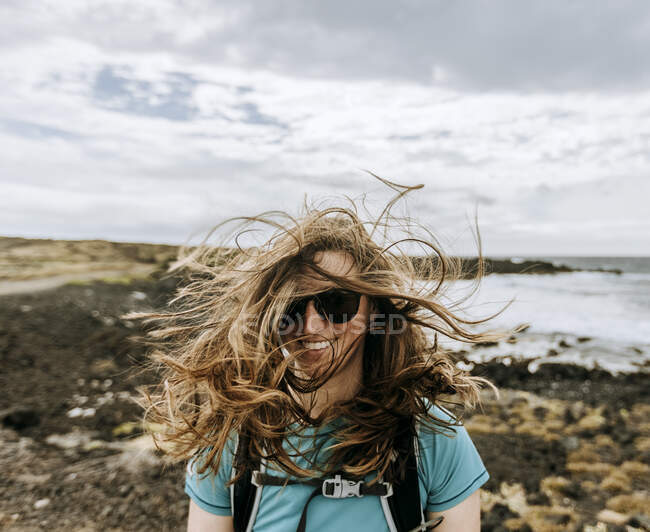 Mulher com cabelo confuso soprado pelo vento sorri enquanto caminha no Havaí — Fotografia de Stock