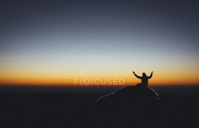 Silhouette of man over car at sunrise — Stock Photo