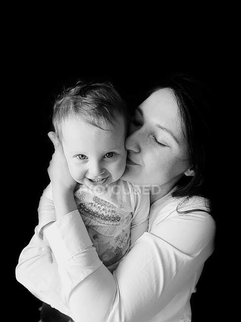 Ritratto in bianco e nero di madre che abbraccia e bacia ragazza sorridente — Foto stock