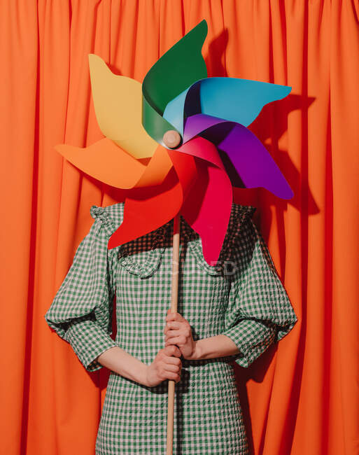 Stilvolle Frau in grünem Kleid mit Windrad auf orangefarbenen Vorhängen — Stockfoto