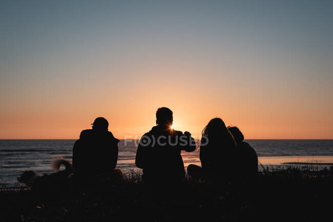 Amigos disfrutando de una puesta de sol en la playa - foto de stock