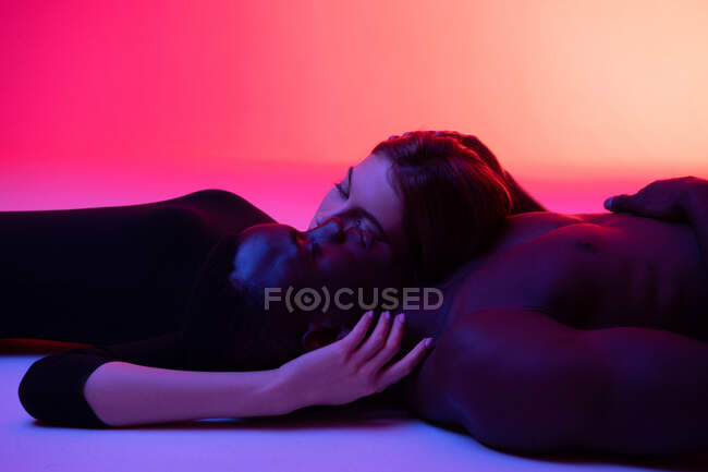 Diversa pareja en el amor relajarse en el piso del estudio - foto de stock