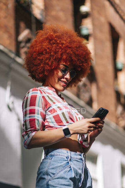 Латинская женщина с афроволосами с помощью мобильного телефона — стоковое фото