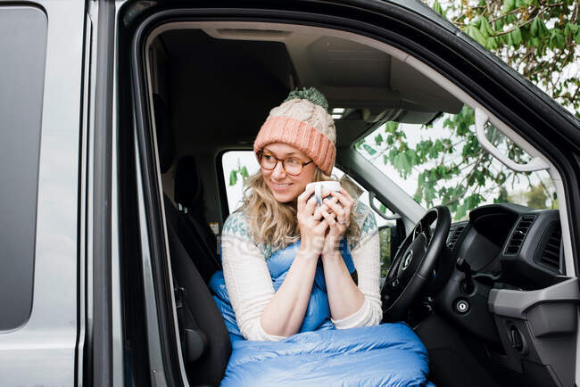 Woman sat in her van drinking a cup of coffee enjoying the morning — Stock Photo