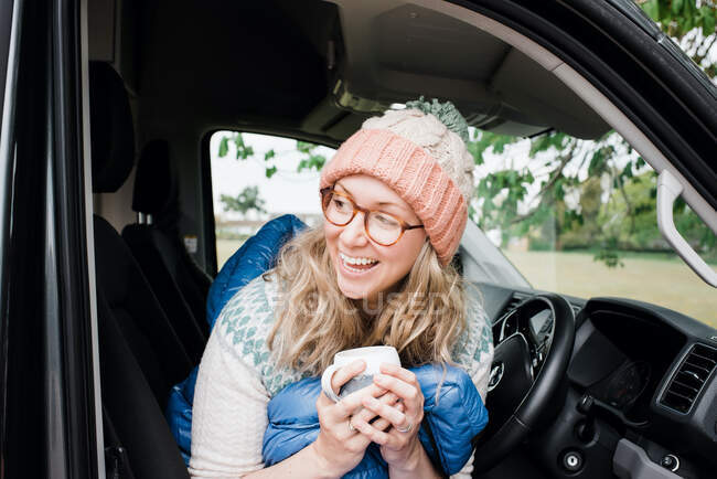 Mulher sentou-se em sua van campista rindo alegremente enquanto bebia café — Fotografia de Stock