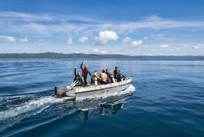 Buceadores se dirigen a punto de buceo en bote bote en Raja Ampat - foto de stock